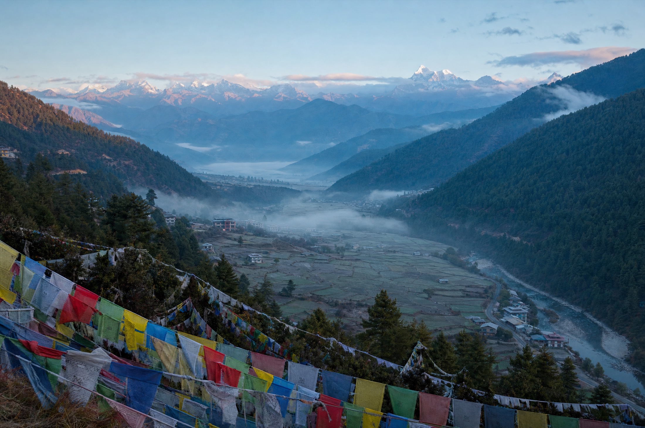 The Thimphu valley at dawn, prayer flags in the foreground and Himalayan peaks beyond